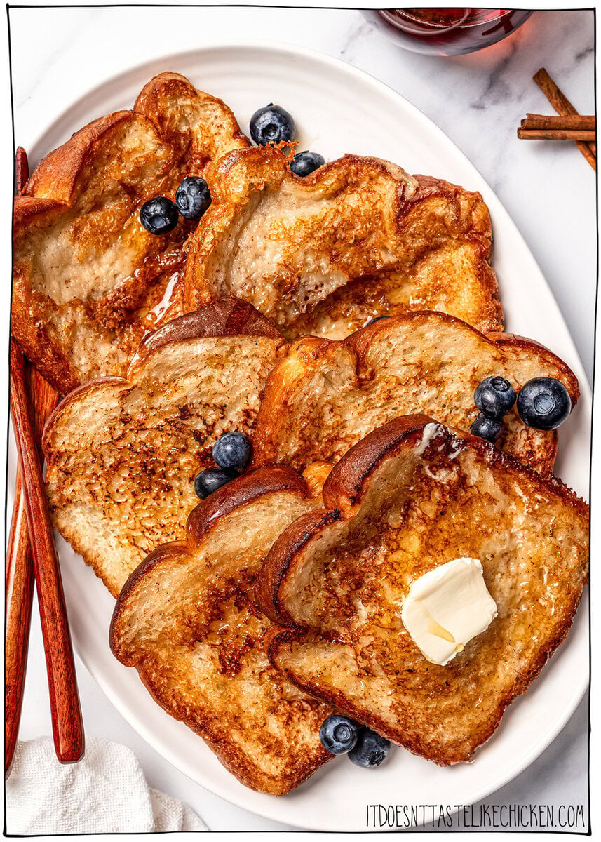 This Vegan French Toast recipe is crispy, fluffy and custardy, just like the classic! It's quick, easy and made with simple ingredients too. Platter of vegan French toast topped with butter and blueberries.