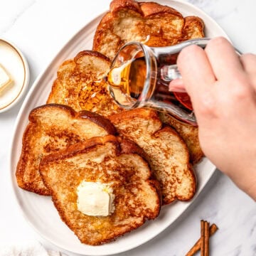Pouring syrup onto platter of vegan French toast.