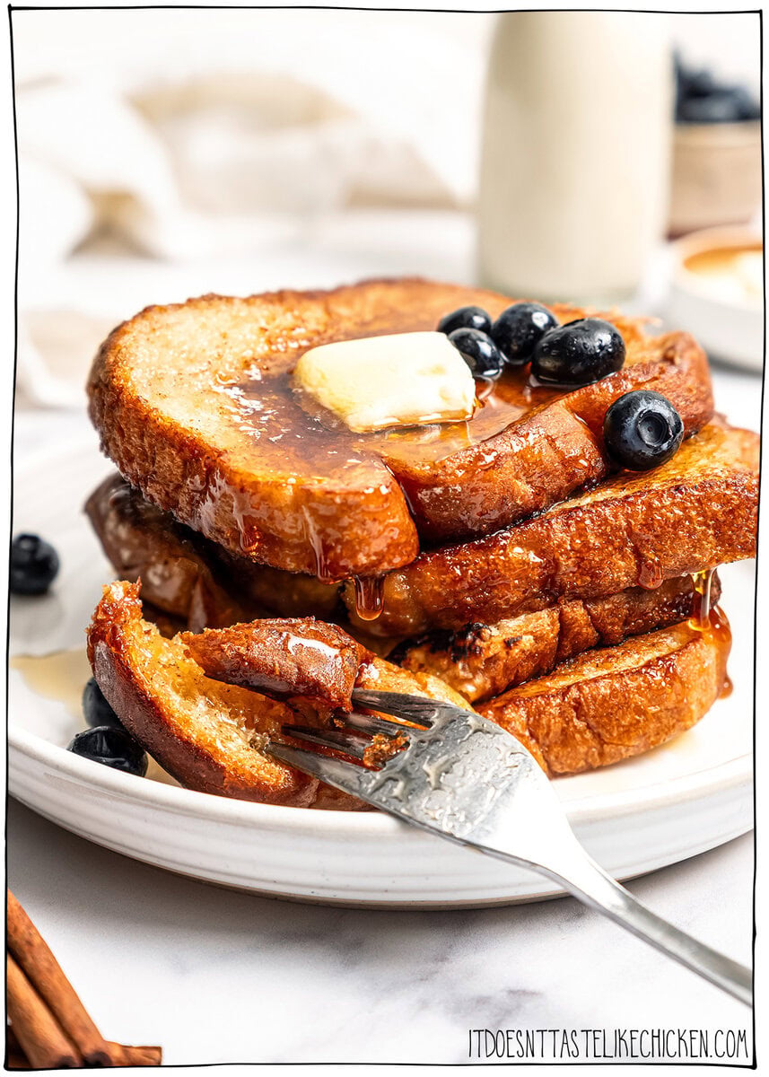 This Vegan French Toast recipe is crispy, fluffy and custardy, just like the classic! It's quick, easy and made with simple ingredients too. Stack of 4 slices of vegan French toast on plate with fork.