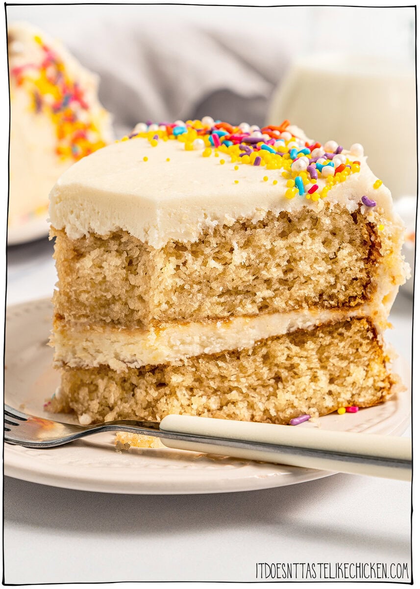 This soft and fluffy vegan vanilla cake recipe is perfect for birthdays and celebrations! It's super easy to make with pantry ingredients. Slice of vegan vanilla cake on plate with fork.