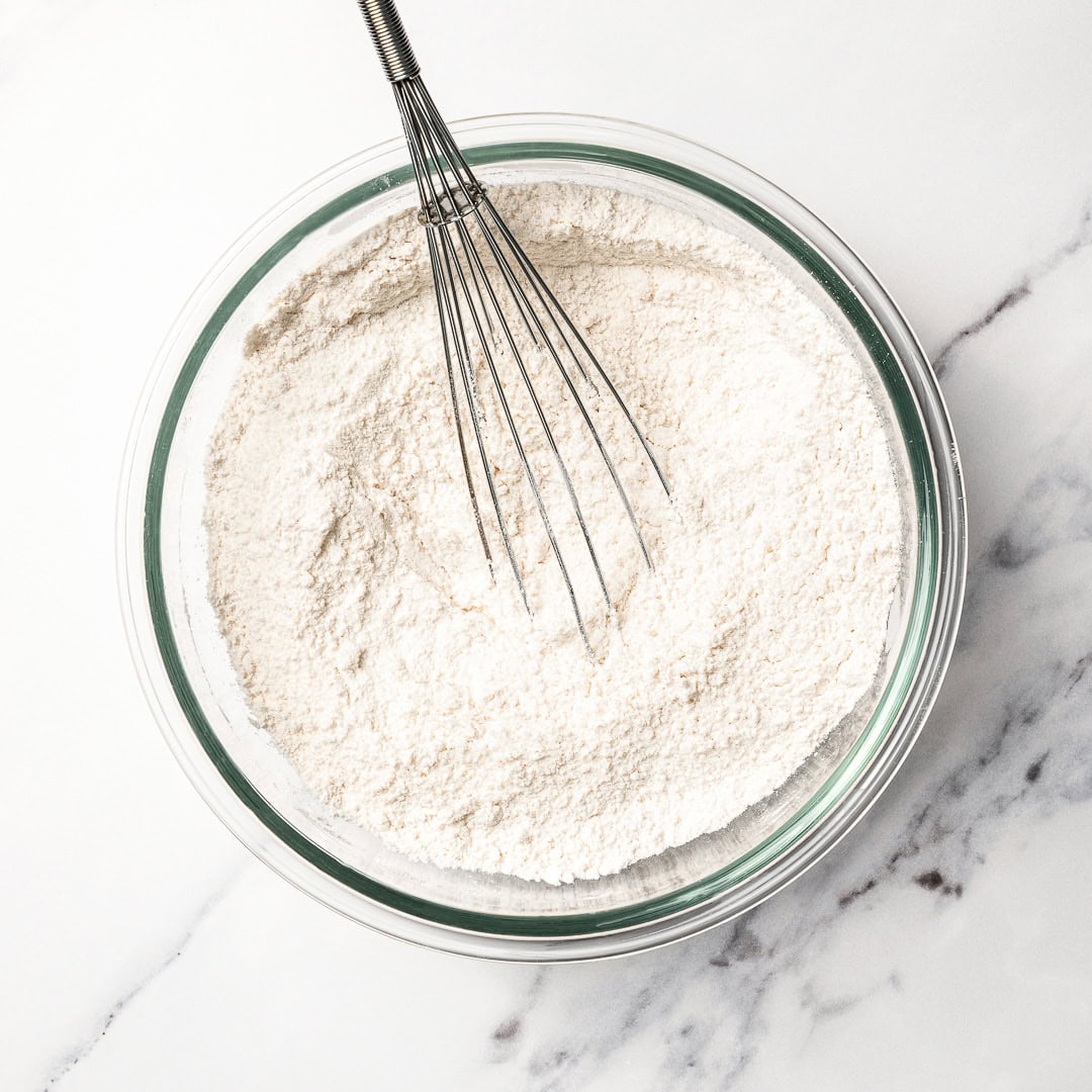 This soft and fluffy vegan vanilla cake recipe is perfect for birthdays and celebrations! It's super easy to make with pantry ingredients. Whisk in bowl with dry cake ingredients.