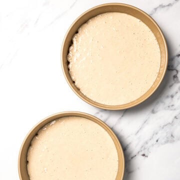 Vegan vanilla cake batter divided into two cake pans.