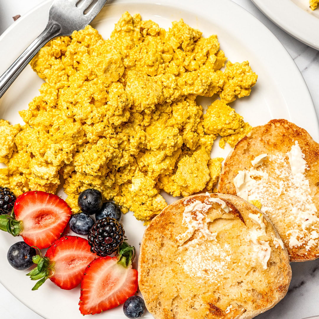 Plate of tofu scramble with English muffins and berries.