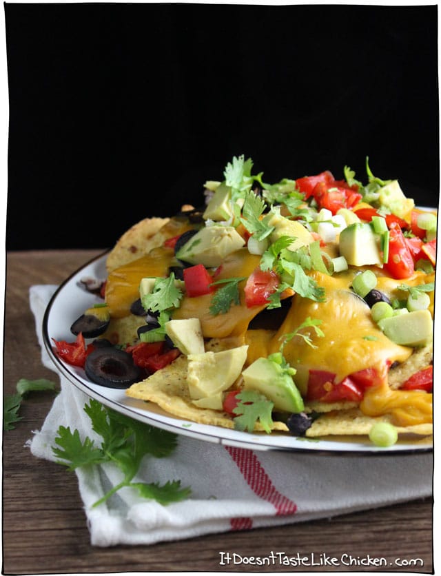 The best damn loaded vegan nachos from here to Timbuktu! Homemade vegan nacho cheese only takes 15 minutes to make, then just load up the tortilla chips will all the best toppings! So easy. #itdoesnttastelikechicken