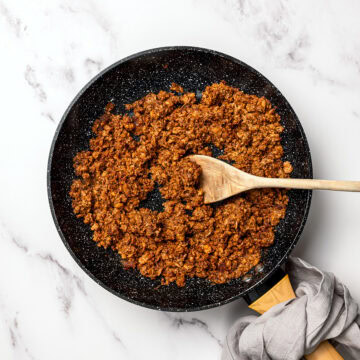 Vegan taco meat in skillet with wooden spoon.