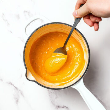 Stirring vegan nacho cheese sauce in pan.