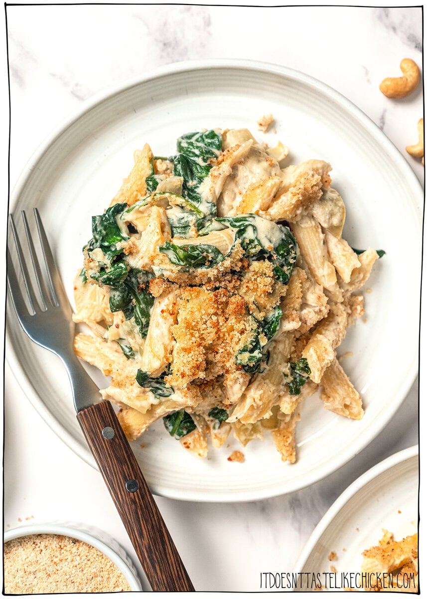 Plate of spinach artichoke pasta bake with fork.