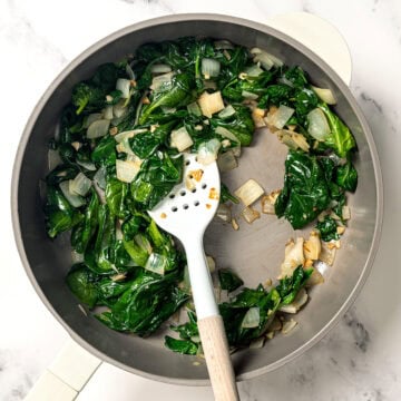 Onion and spinach cooking in skillet.