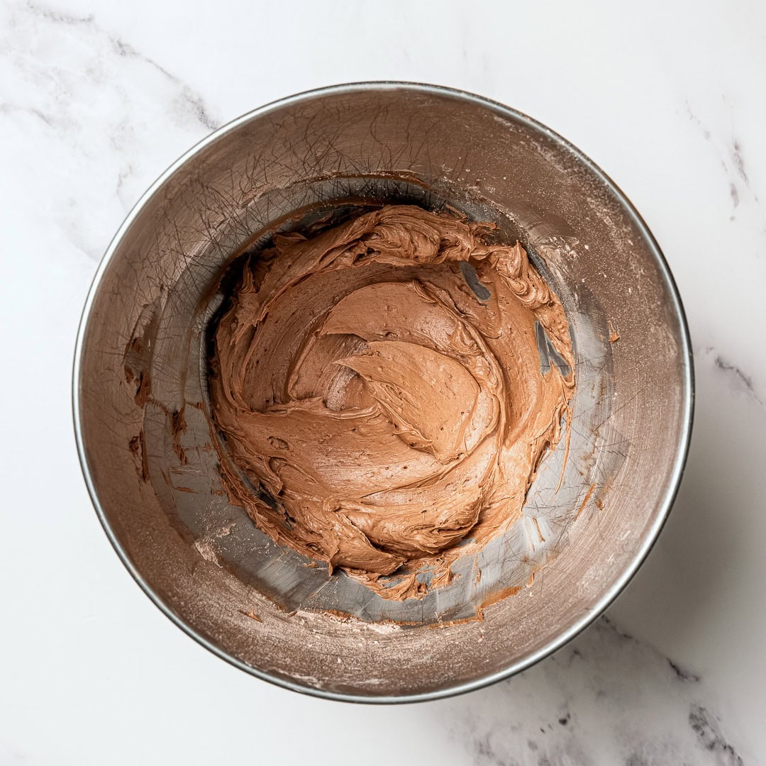 This moist, rich vegan chocolate cake is finished with fluffy chocolate buttercream, perfect for birthdays and holidays. So easy to make too! Vegan chocolate buttercream in mixing bowl.
