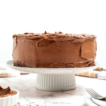 Vegan chocolate cake on cake stand after frosting.