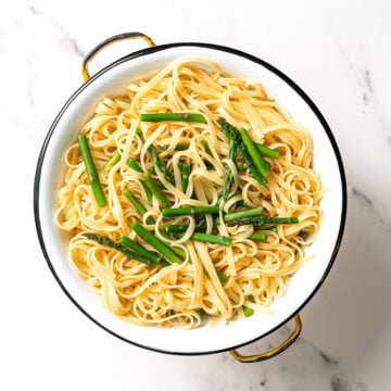 Cooked pasta and asparagus in colander.