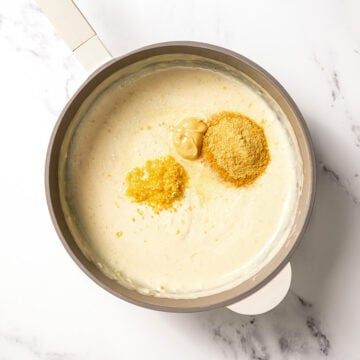 Mustard, lemon zest, and nutritional yeast in skillet with sauce.