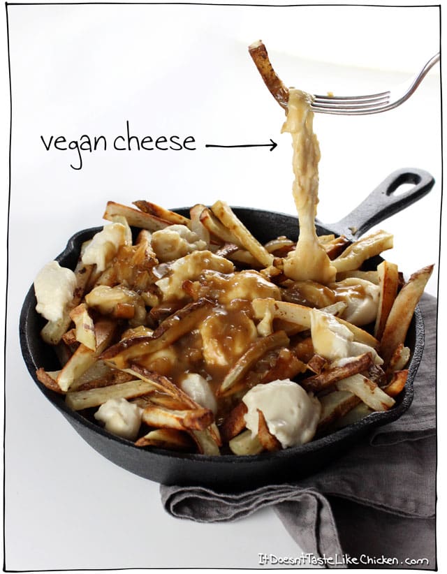 Classic Canadian comfort food: The Ultimate Vegan Poutine. Baked crispy French fries, topped with quick and easy dairy-free cheese curds, smothered in rich onion gravy. #itdoesnttastelikechicken