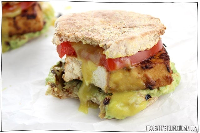 The Ultimate Vegan Breakfast Sandwich! Thick slices of smoky, marinated tofu on an English muffin with mashed avocado, a slice of ripe tomato, and a homemade 5-minute vegan egg yolk inspired sauce. The tofu gets more flavourful the longer it marinates. I just keep it marinating in the fridge, so when morning hunger strikes, it's game on! #itdoesnttastelikechicken #veganrecipes #veganbreakfast #eggfree