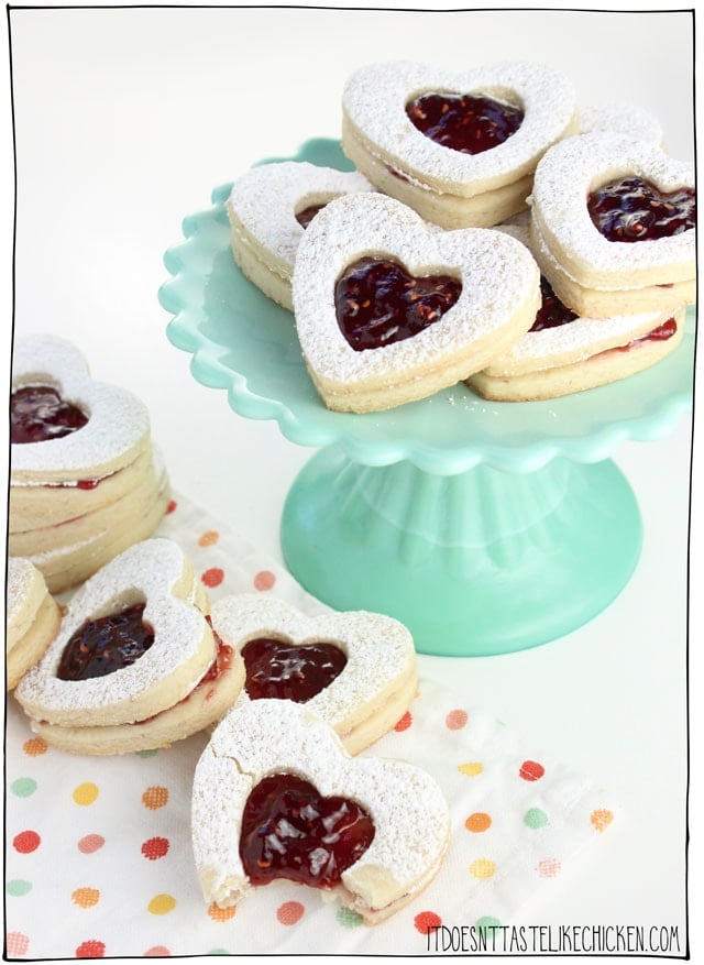 Vegan Linzer Heart Cookies! The buttery soft sugar cookie, sprinkled with powdered sugar, filled with sweet raspberry jam. They are every bit as tasty as they are adorable. Perfect for a gift for a loved one on Valentine's day or other special occasions. Egg-free, dairy-free. #itdoesnttastelikechicken #valentinesday #veganvalentines #veganbaking