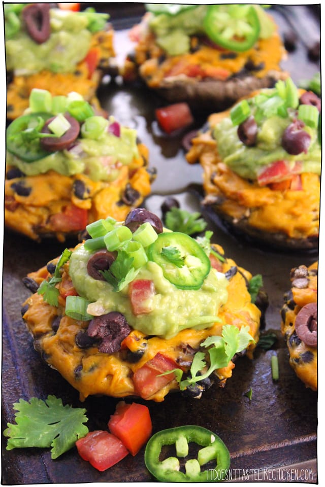 Vegan Nacho Stuffed Portobellos! Portobello mushrooms are stuffed with a homemade vegan nacho cheese filled with black beans and tomato. Bake or grill the mushrooms then top with guacamole for a fiesta in your mouth! Makes a great main when paired with Mexican rice and corn on the cob. #itdoesnttastelikechicken #veganrecipes #veganmains