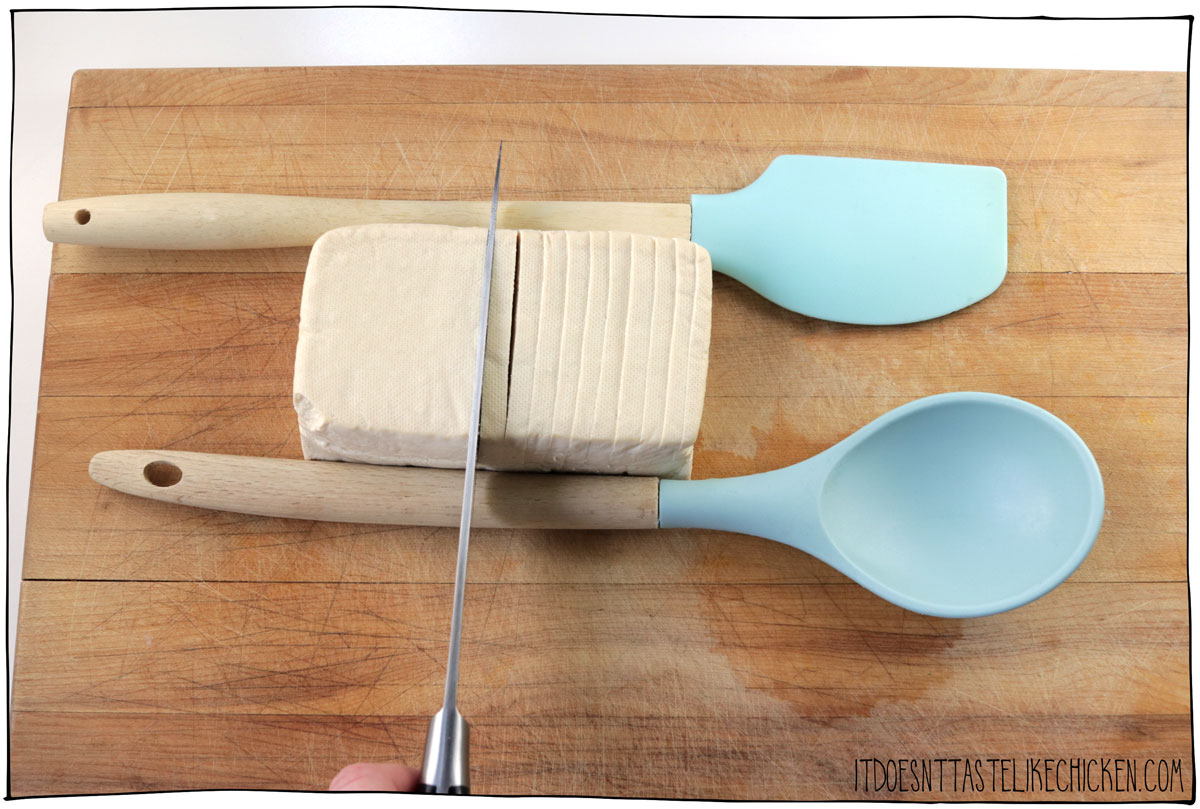 Place a wooden spoon handle on either side of the tofu and slice the tofu partway 