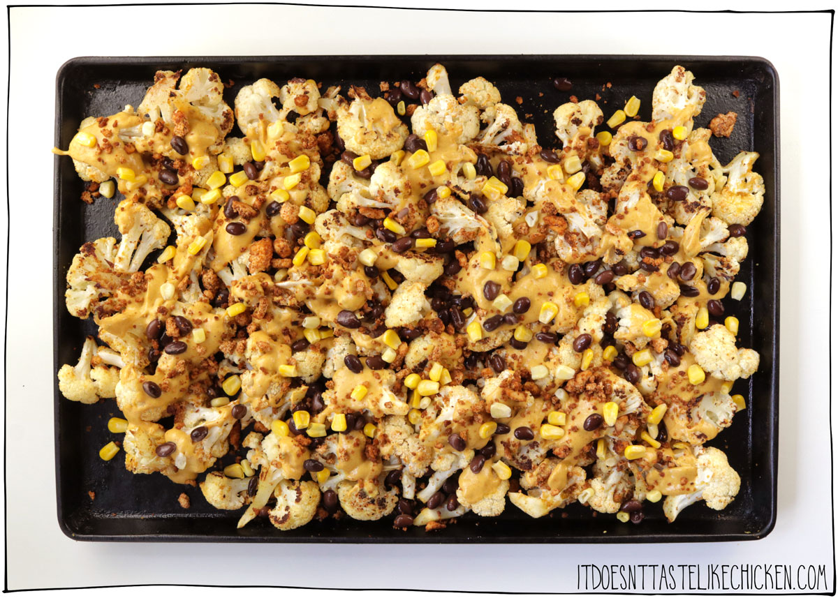 Top the cauliflower with vegan taco meat, black beans, corn, and nacho cheese and bake again
