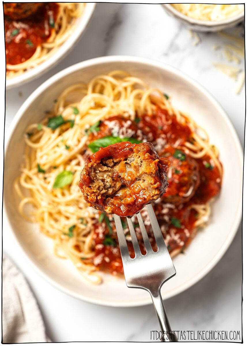 Vegan meatball on fork with bite taken out to show texture inside.