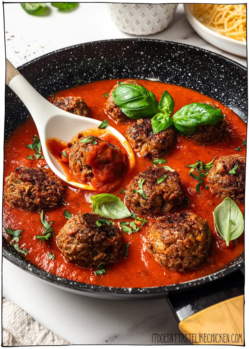 Vegan meatball being scooped out of skillet with spoon.