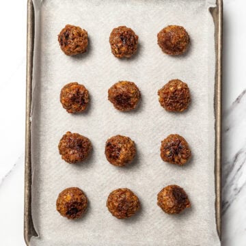 Vegan meatballs on parchment lined baking sheet.