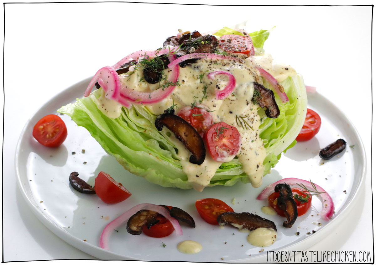 This vegan wedge salad recipe is topped with vegan bacon bits, cherry tomatoes, pickled red onions, and an incredibly delicious homemade vegan blue cheese salad dressing!  This recipe is quick and easy to make (it takes less than 15 minutes) and is perfect for a fancy-looking appetizer or side dish.  #itdoesnttastelikechicken #salad #veganrecipes