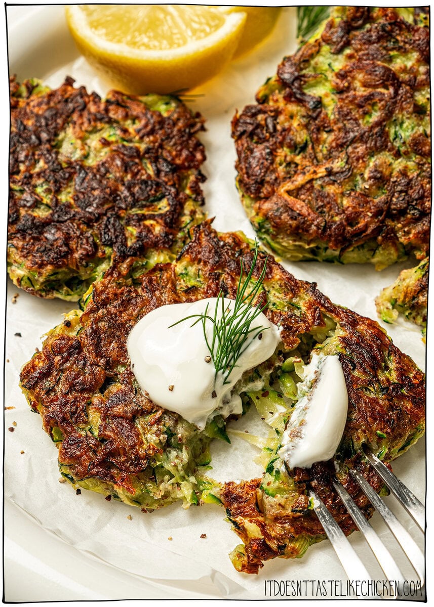 Zucchini fritter topped with vegan sour cream, cut in half.