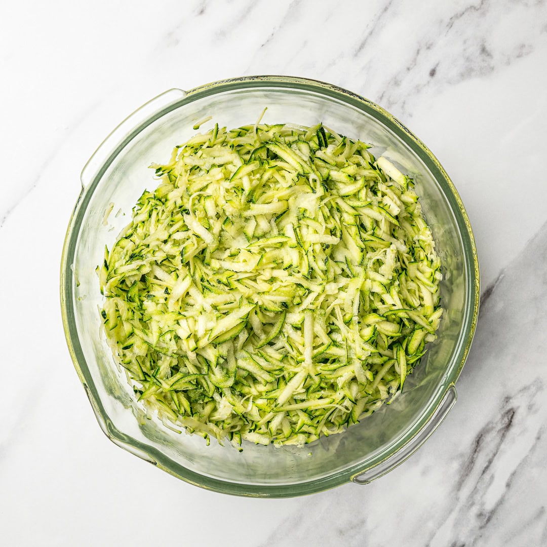 Shredded zucchini in glass bowl.