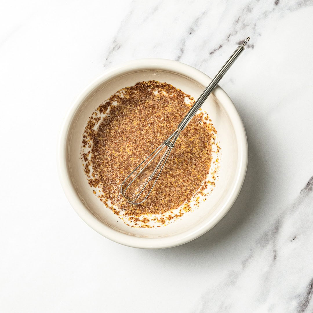Flax egg mixture in bowl with whisk.