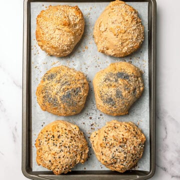Vegan protein bagel buns on parchment lined sheet pan.