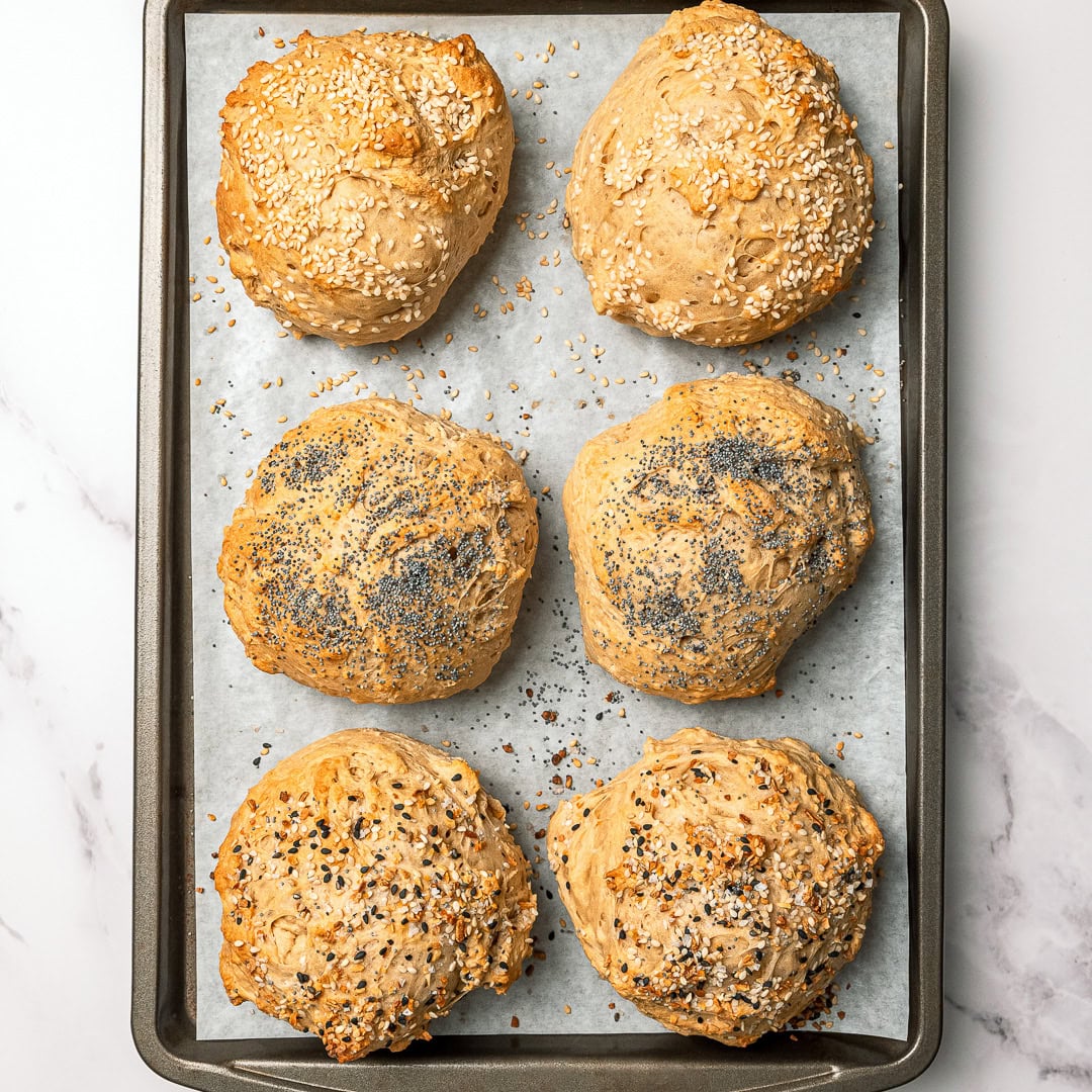 Vegan protein bagel buns on parchment lined sheet pan.