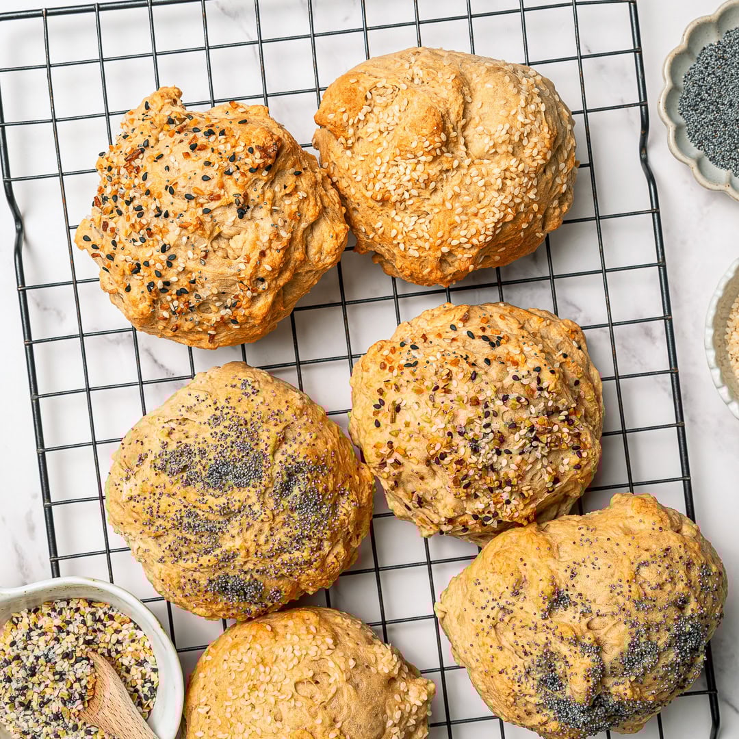 Overhead view of protein bagel buns on wire cooling rack.