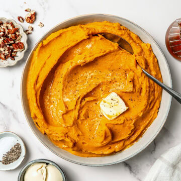 Maple-tahini mashed sweet potatoes in serving dish with spoon.