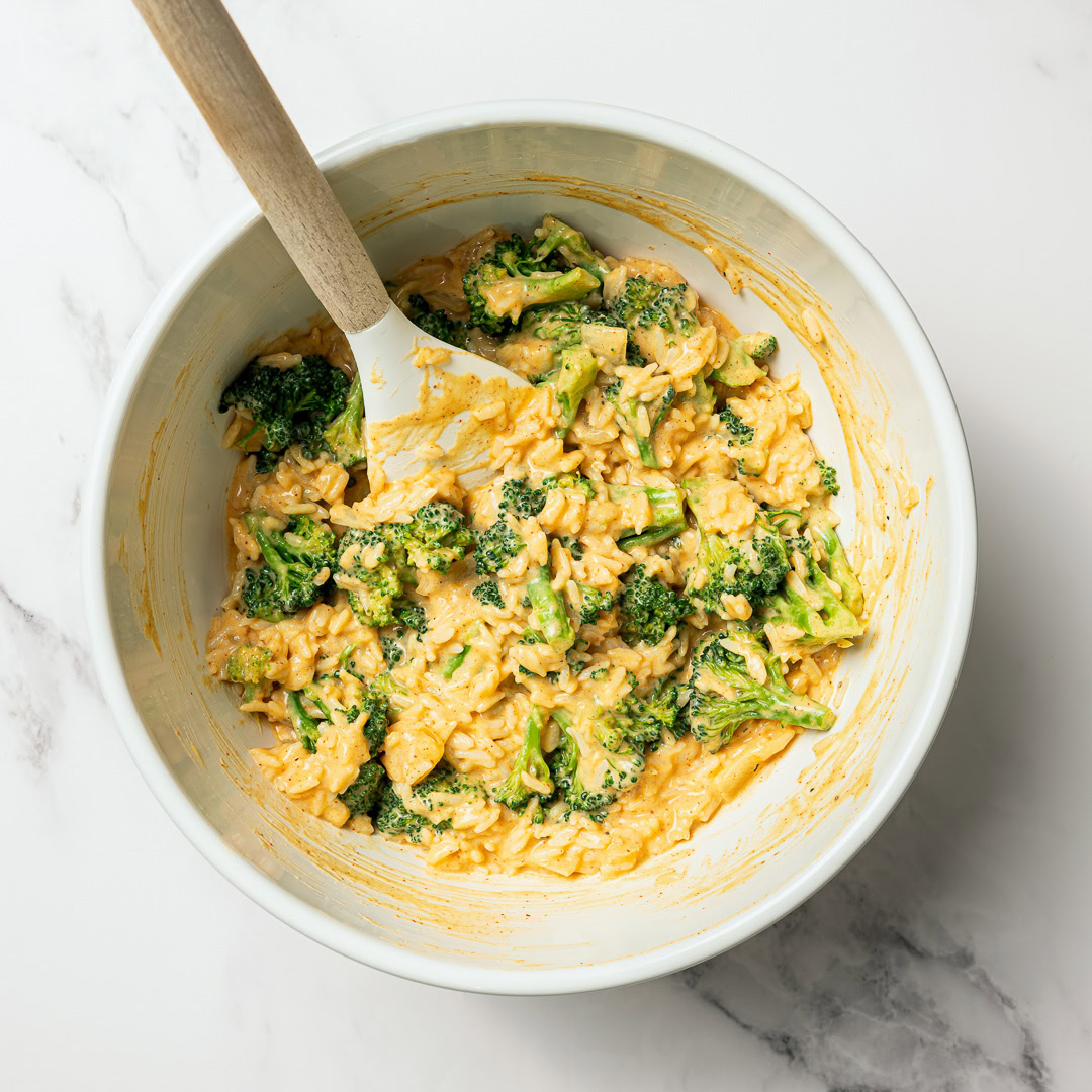 This easy Vegan Broccoli Rice Casserole is a crowd-pleaser with creamy cheese sauce, broccoli and fluffy rice. Works as a main dish or side! Cheesy rice and broccoli mixture in mixing bowl.
