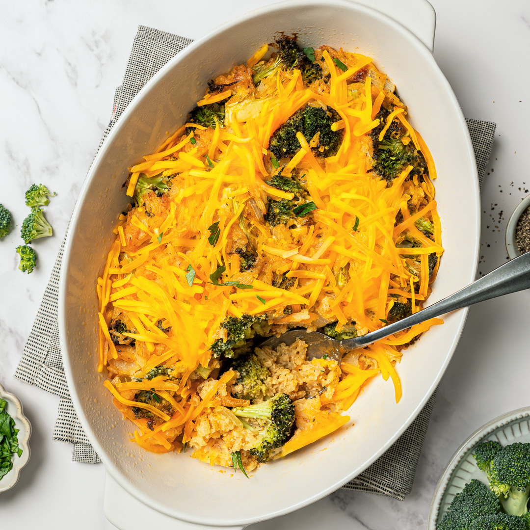 This easy Vegan Broccoli Rice Casserole is a crowd-pleaser with creamy cheese sauce, broccoli and fluffy rice. Works as a main dish or side! Spoon in baking dish with vegan broccoli rice casserole.