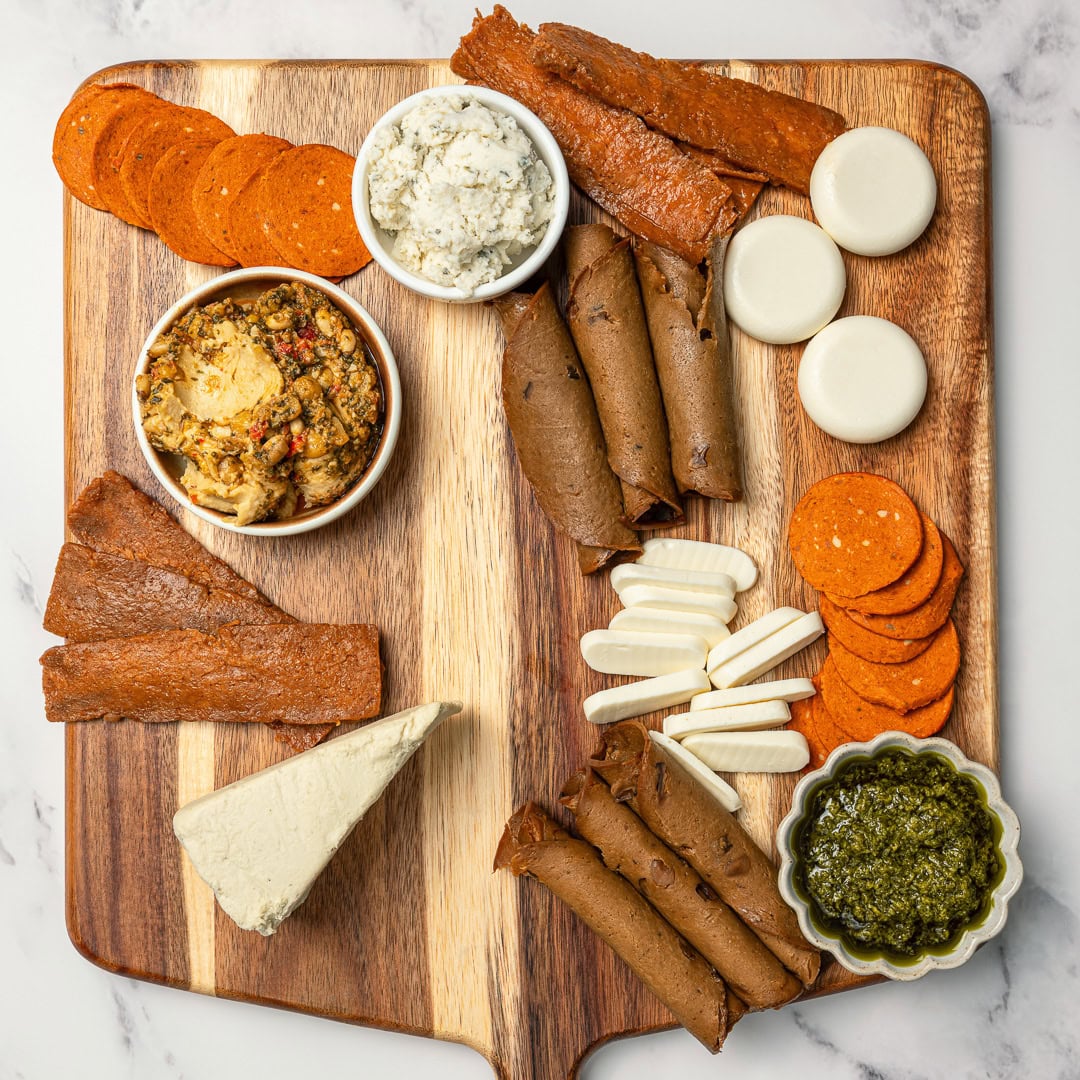 Filled with plant-based cheeses, dips, fruits and crunchy snacks, this easy vegan charcuterie board is the ultimate holiday appetizer! Vegan charcuterie board in progress, with vegan meats, cheeses, and dips.