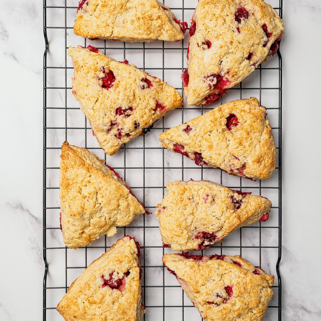 These easy Vegan Cranberry Orange Scones are flaky, citrusy, and full of festive flavor. Perfect for holiday brunches or a cozy winter treat! Cranberry orange scones on wire rack.