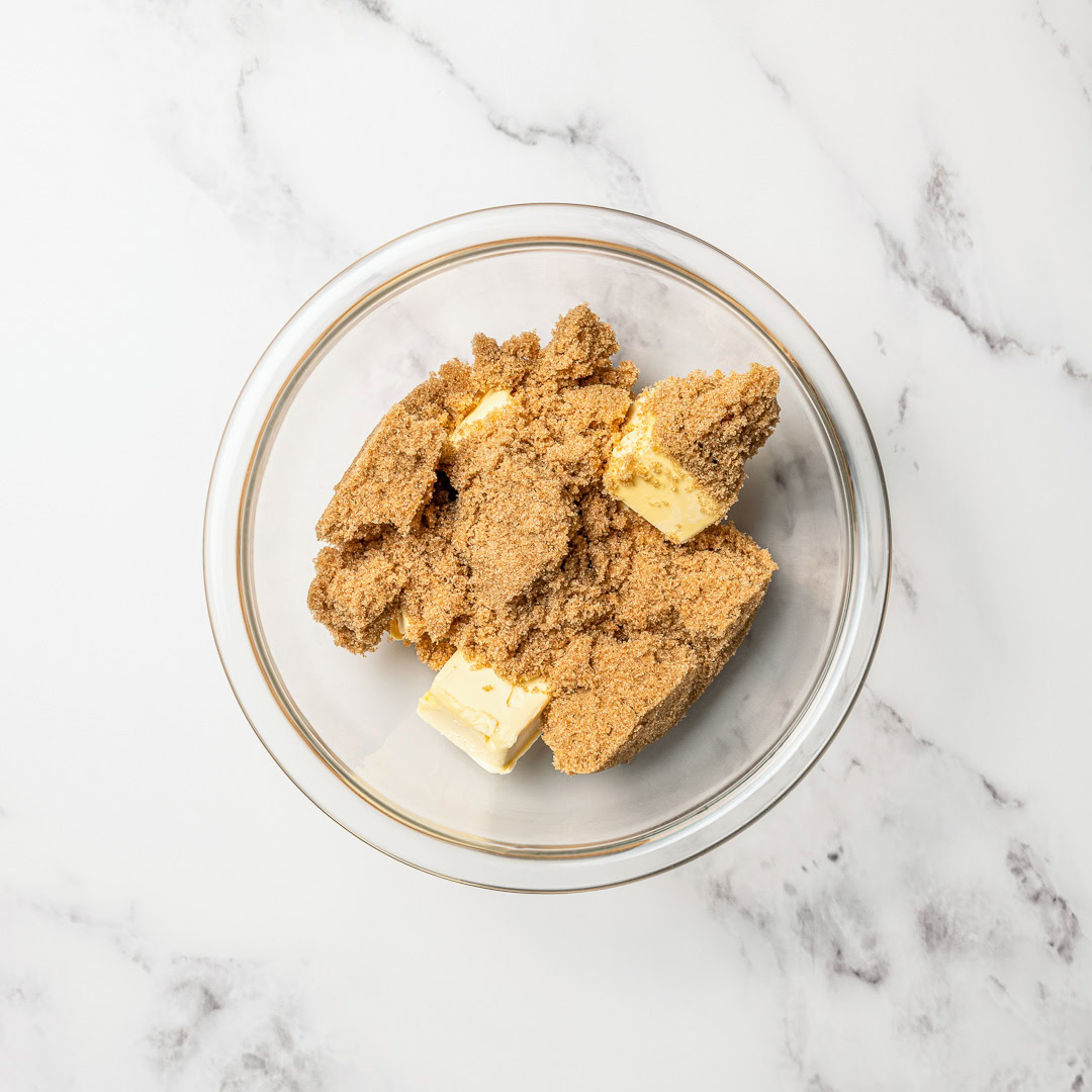 Soft, chewy and perfectly spiced, these vegan gingerbread cookies are made with rich molasses and warm spices. Easy to roll, cut and decorate! Vegan butter and brown sugar in glass bowl.