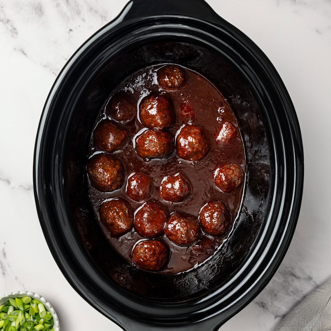 Vegan Grape Jelly Meatballs are sweet, tangy, and effortless! An easy crowd-pleasing slow cooker appetizer perfect for parties and holidays. Vegan grape jelly meatballs in slow cooker insert.