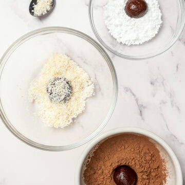 Rum balls in 3 bowls of coatings: powdered sugar, coconut, and cocoa powder.