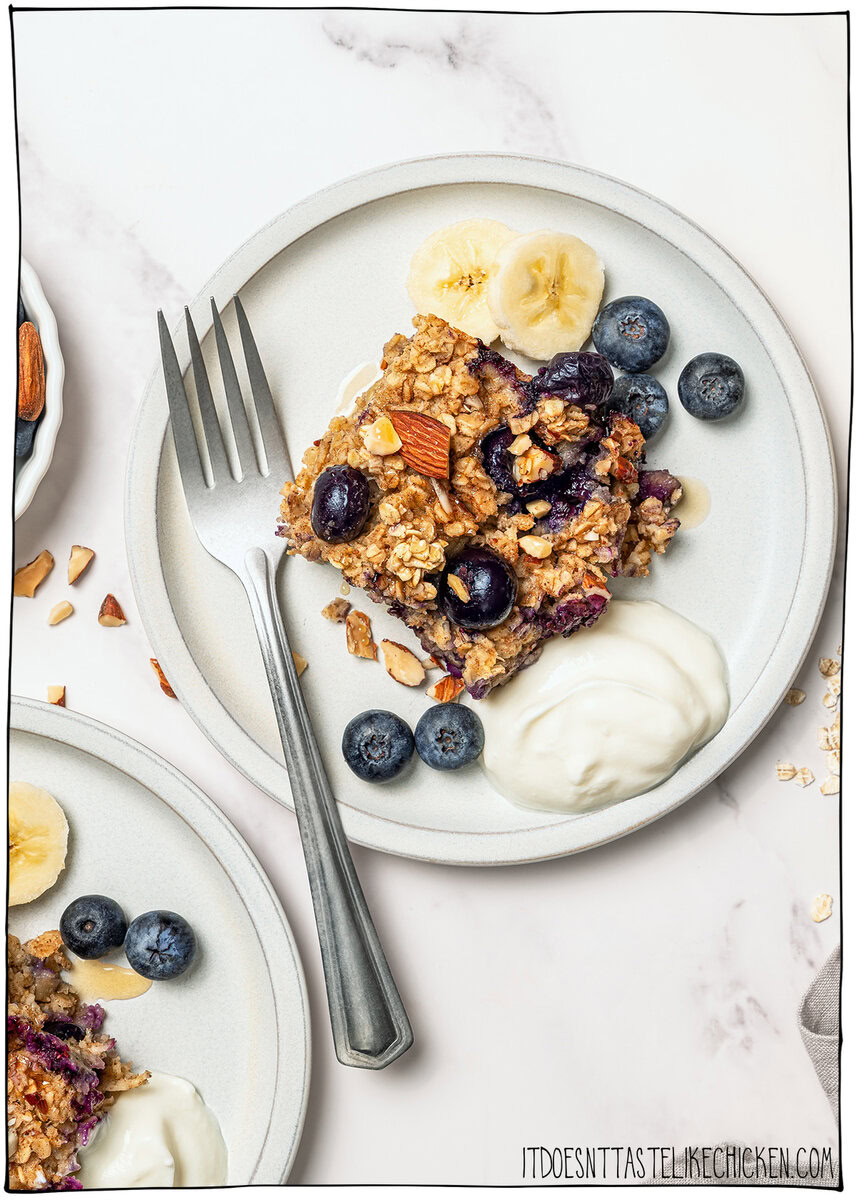 This cozy vegan baked oatmeal is easy to make, customizable, and perfect for meal prep. Mix in one bowl and enjoy any flavor combo! Plate of vegan baked oatmeal with yogurt, blueberries, and bananas.