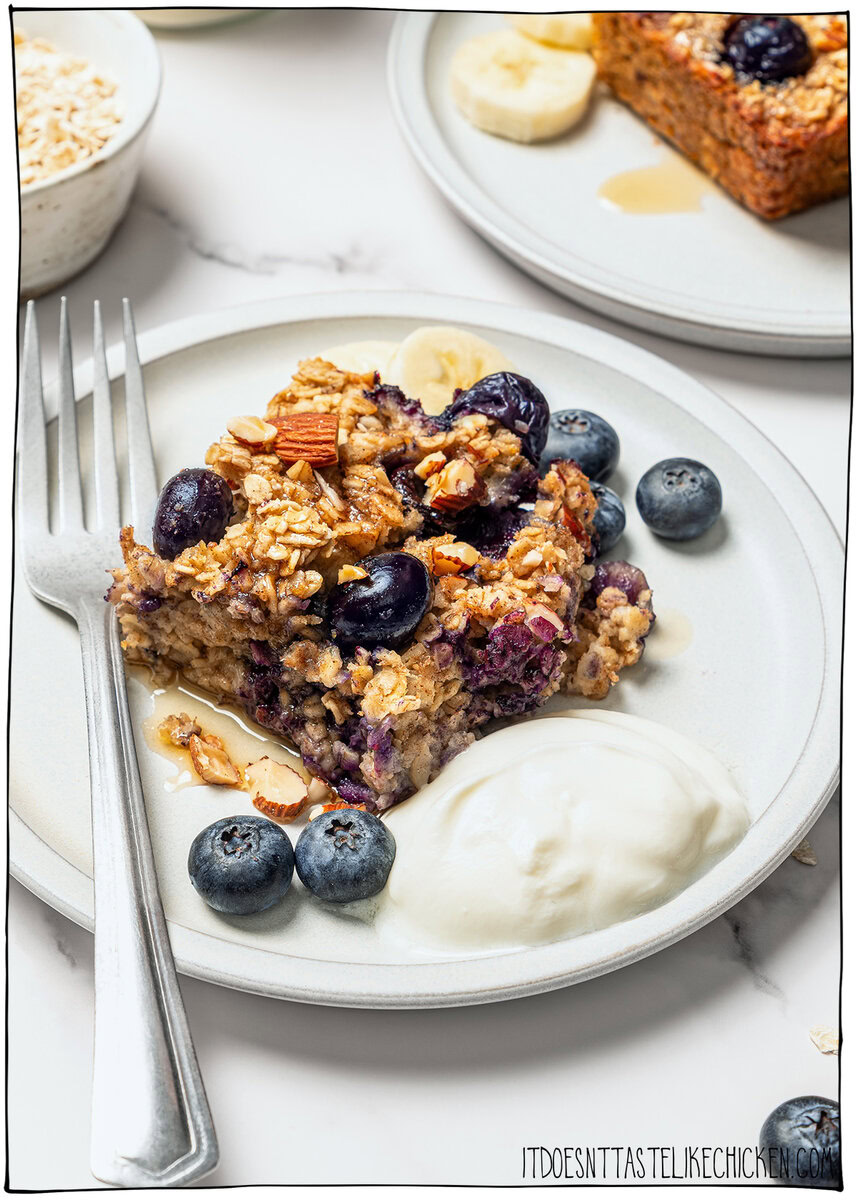 This cozy vegan baked oatmeal is easy to make, customizable, and perfect for meal prep. Mix in one bowl and enjoy any flavor combo! Baked oatmeal on plate with vegan yogurt.