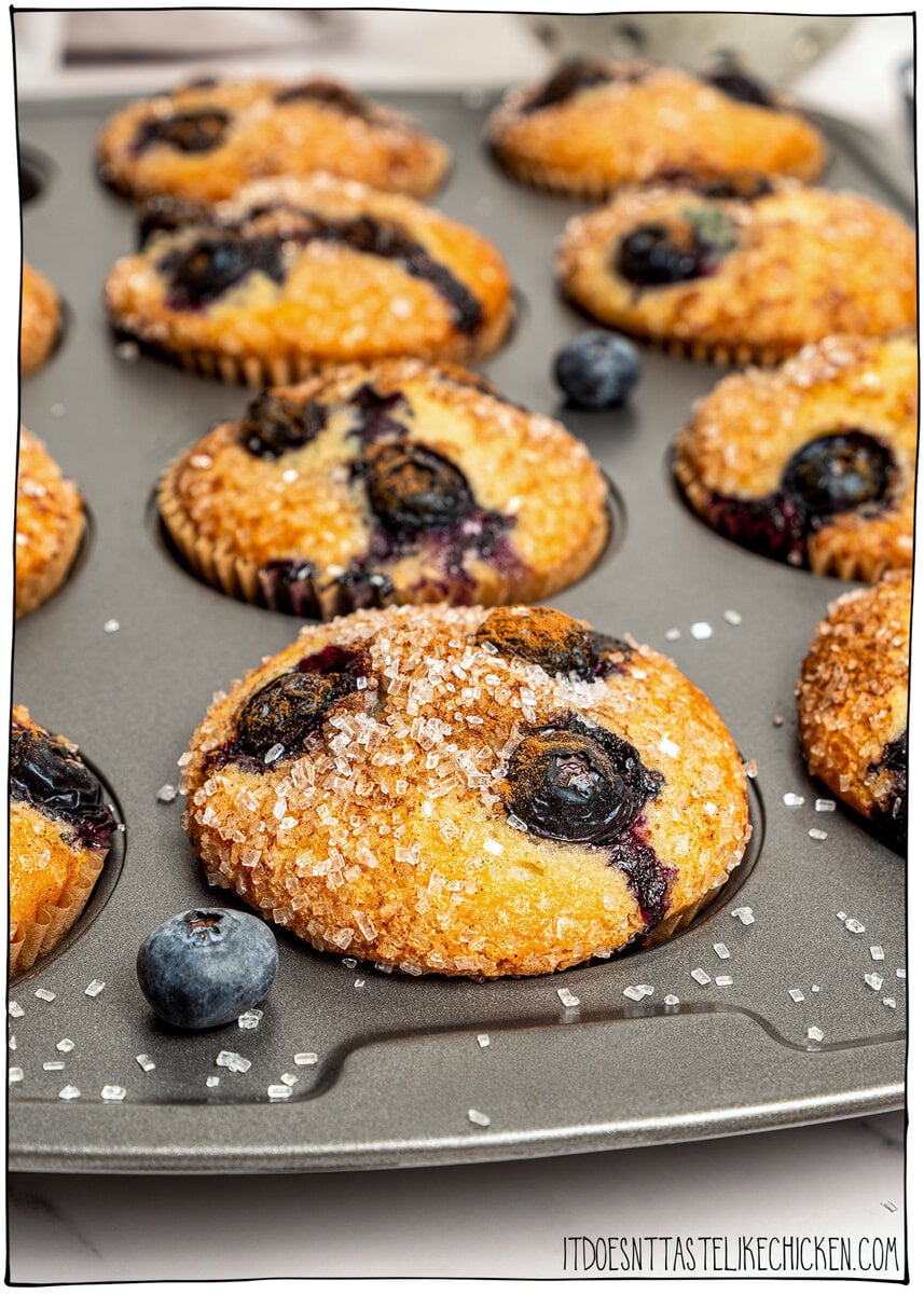 These bakery-style vegan blueberry muffins are made in one bowl, super easy! They're soft, fluffy, and finished with a crunchy sugar top. Vegan blueberry muffins in pan with sparkling sugar topping.