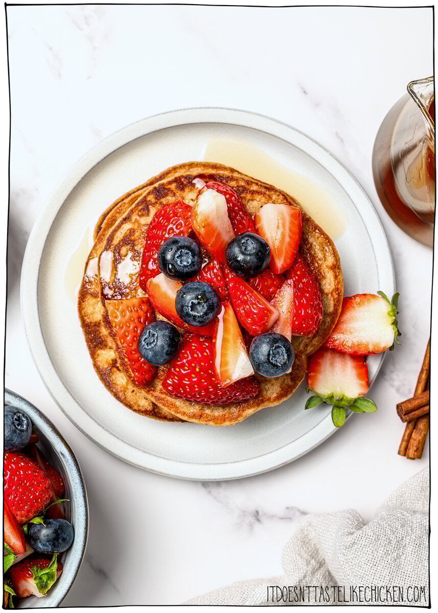 These fluffy vegan protein pancakes are mixed in the blender for an easy healthy breakfast with skillet or sheet-pan options. Gluten-free too! Overhead view of vegan protein pancakes topped with blueberries and strawberries.