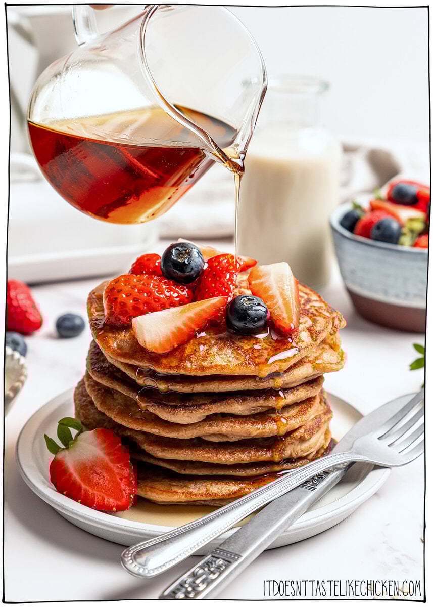 These fluffy vegan protein pancakes are mixed in the blender for an easy healthy breakfast with skillet or sheet-pan options. Gluten-free too! Pouring maple syrup over stack of vegan protein pancakes.