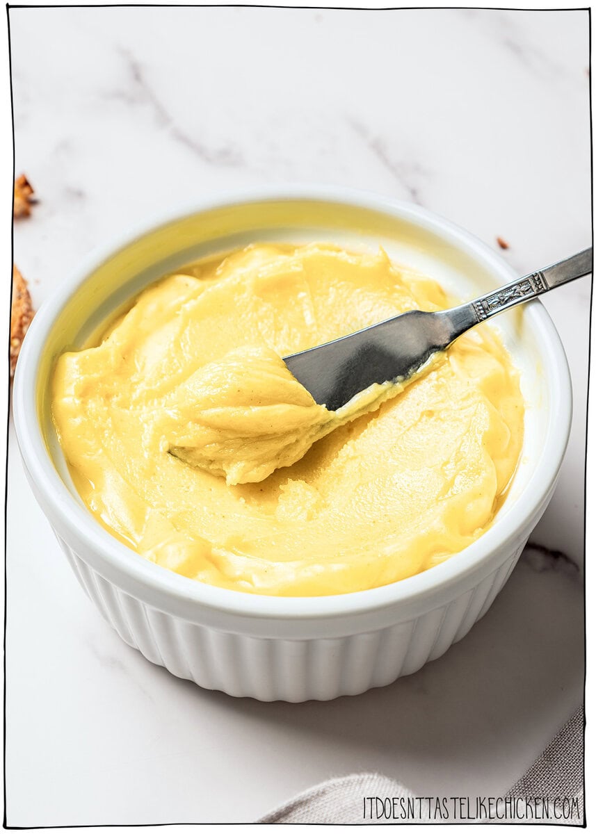This homemade vegan butter melts, spreads and tastes like the real thing! Easy to make with everyday ingredients, you can even bake with it. Butter knife in bowl of homemade vegan butter.