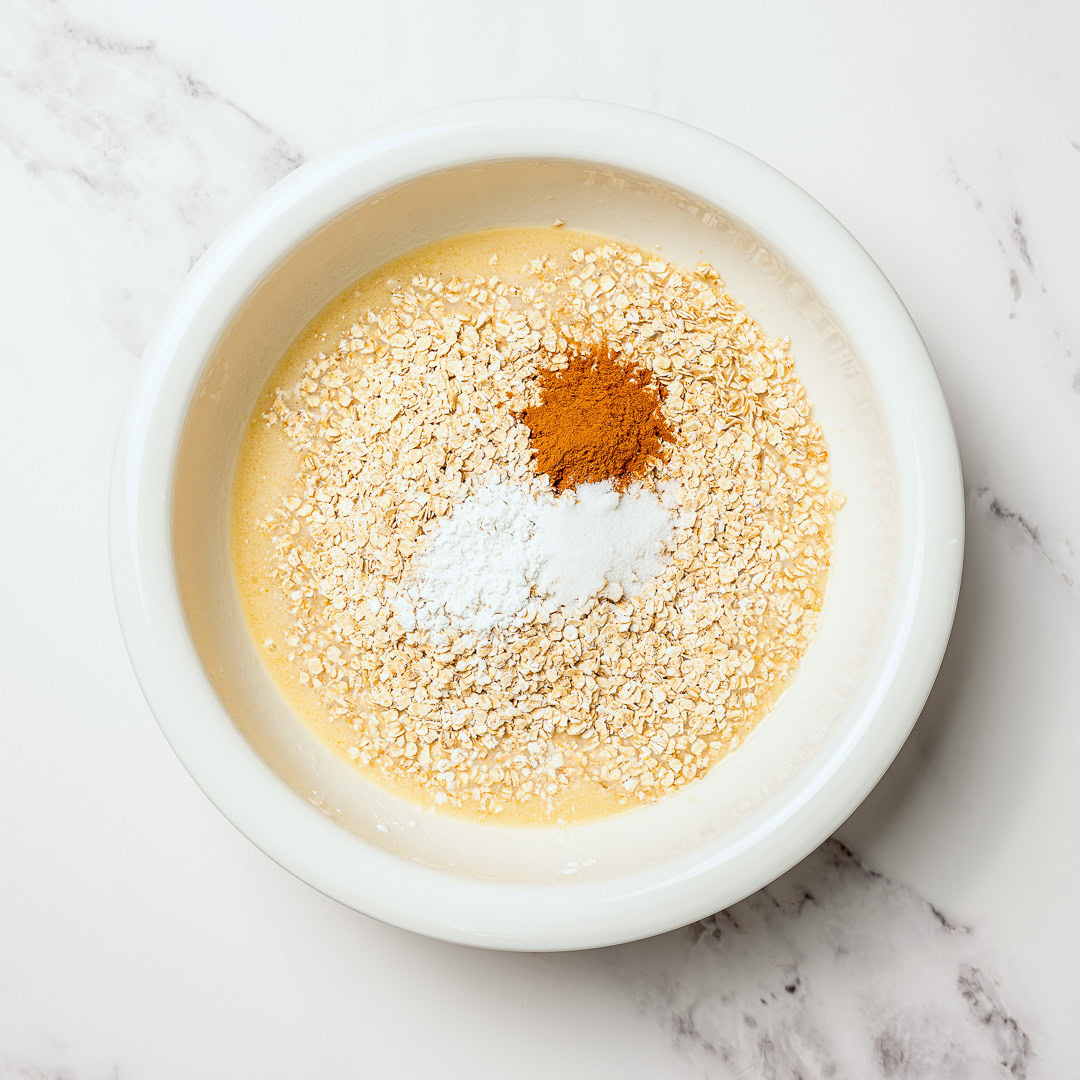 This cozy vegan baked oatmeal is easy to make, customizable, and perfect for meal prep. Mix in one bowl and enjoy any flavor combo! Dry ingredients for baked oatmeal added to bowl of wet ingredients.