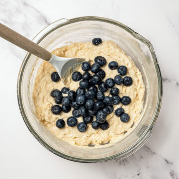 Blueberries added to bowl of muffin batter.