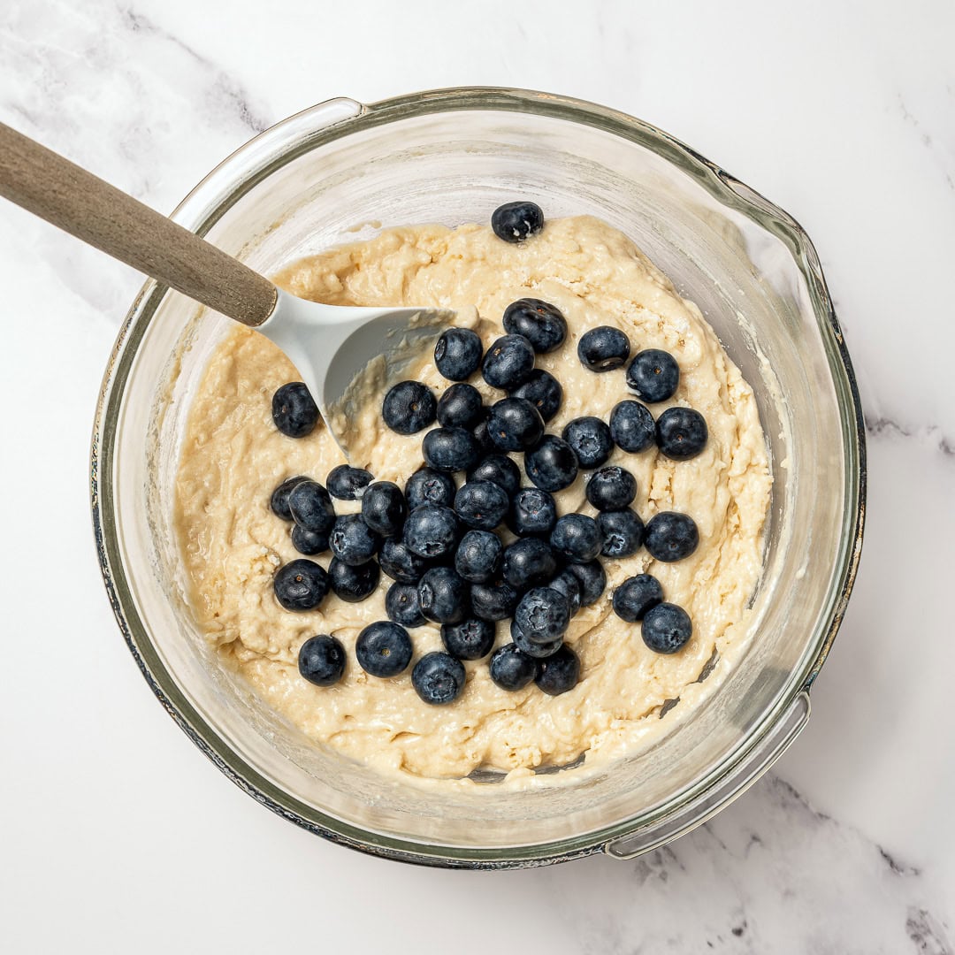 These bakery-style vegan blueberry muffins are made in one bowl, super easy! They're soft, fluffy, and finished with a crunchy sugar top. Blueberries added to bowl of muffin batter.