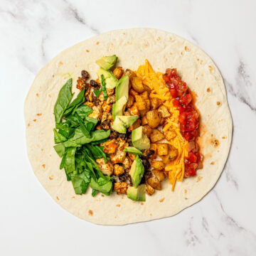 Vegan breakfast burrito fillings on tortilla.